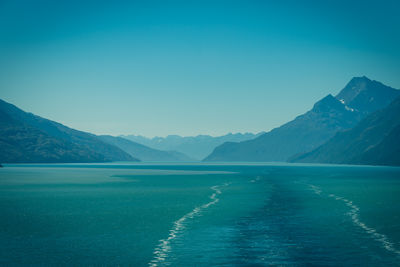 Scenic view of sea and mountains against clear blue sky