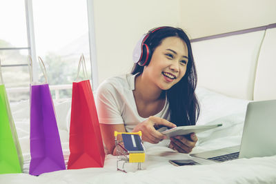 Happy young woman using phone while sitting on laptop
