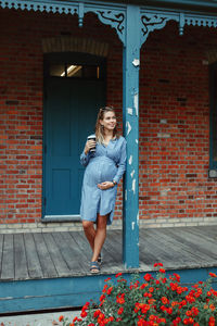 Full length of pregnant woman standing against house