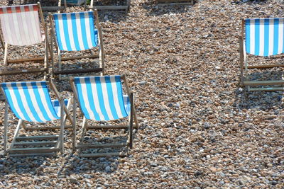 High angle view of empty deck chairs on sunny day at beach
