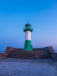 Lighthouse by building against clear blue sky