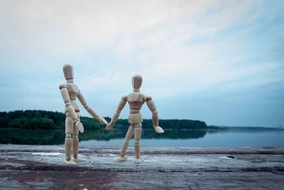 Wooden figurines on table against calm lake