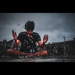 Full length of boy splashing in swimming pool