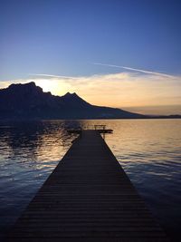 Pier over lake against sky during sunset