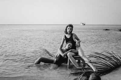 Side view of young woman sitting in sea