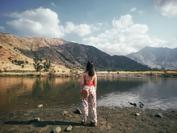 Woman standing by lake against sky