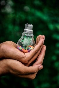 Cropped hands of people holding light bulb with decoration