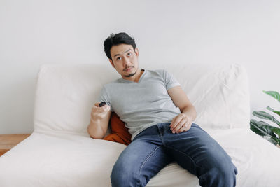 Young woman sitting on bed at home