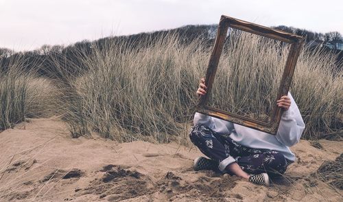 Midsection of man holding umbrella on field