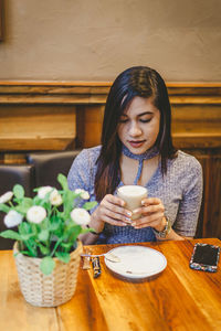 Young woman holding coffee cup on table