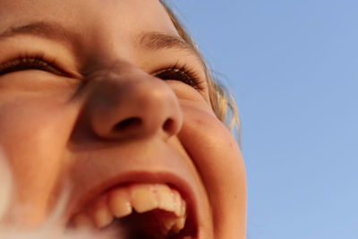 Close-up of happy girl laughing against clear sky