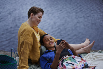 Female couple using phone by river