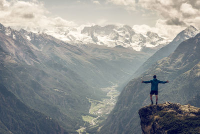 Rear view of man standing on mountain against sky