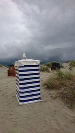 Hooded beach chairs on field against sky