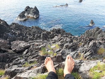 Low section of people relaxing on rock in sea