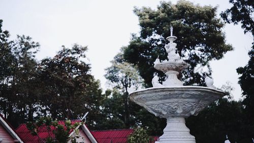 Low angle view of fountain against trees against clear sky