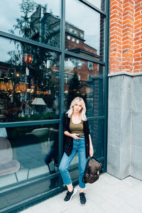 Portrait of woman smiling while standing against store