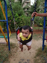Cheerful baby girl on swing at playground