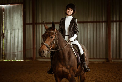 Portrait of smiling young woman riding horse