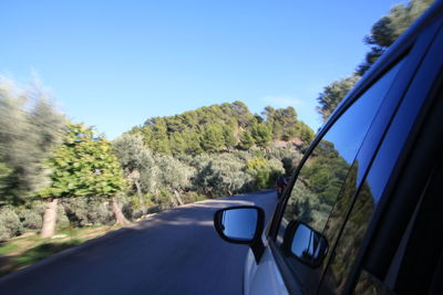 Cars on road against clear blue sky seen through car windshield