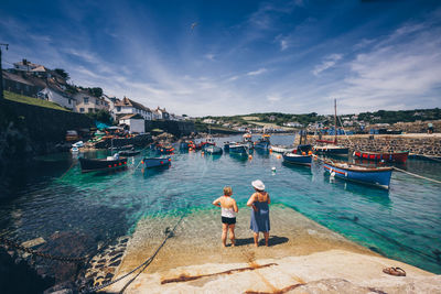 People standing on harbor by sea against sky