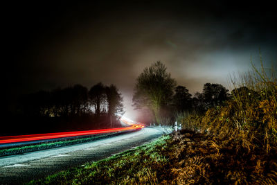 Light trails on road against sky at night