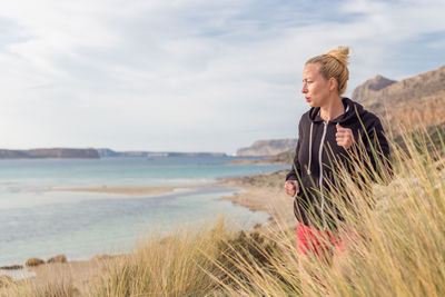 Woman looking at sea shore against sky