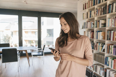 Smiling woman looking at cell phone at home