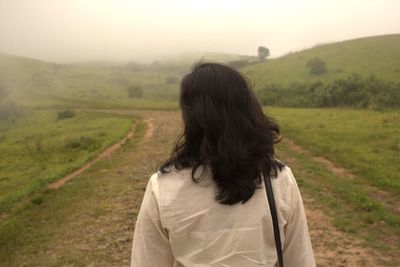 Rear view of woman walking on field