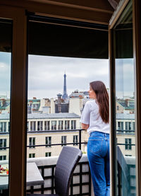 Back view of girl with long hair standing of balcony enjoying view at eiffel tower in paris.