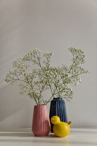 Flower vase on table against wall