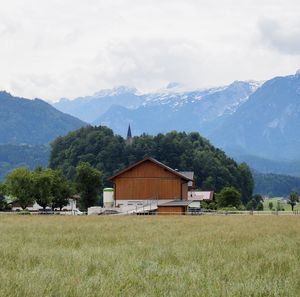 House on field by mountains against sky