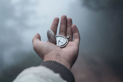 Cropped hand holding pocket watch