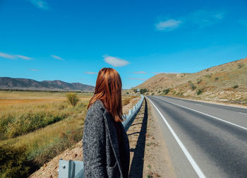 Woman looking away while standing on road