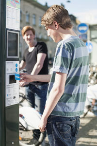 Young man paying through credit card at bicycle sharing system