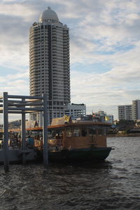 Modern buildings by sea against sky in city