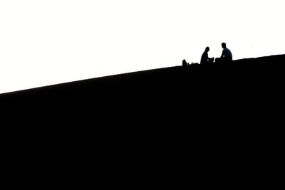 Low angle view of silhouette people against clear sky