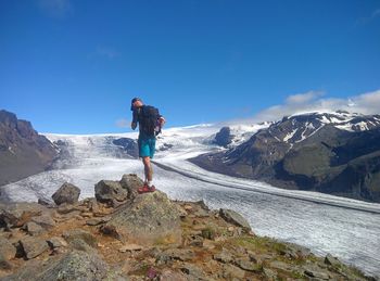 Rear view of man standing on mountain against clear blue sky