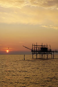 Silhouette pier over sea against sky during sunset