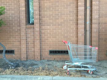 Abandoned shopping cart on footpath against built structure