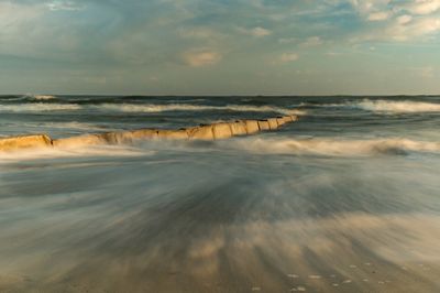 Long exposure of water in sea against cloudy sky during sunset