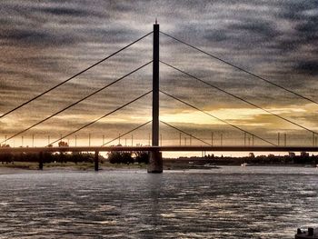 Bridge over river against cloudy sky