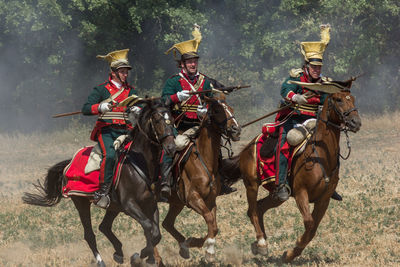 Men riding horse on field