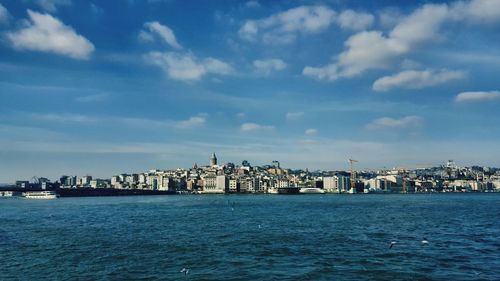 Sea by buildings against blue sky