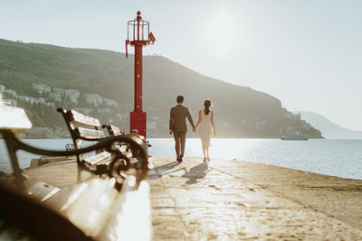 Couple walking at beach against clear sky