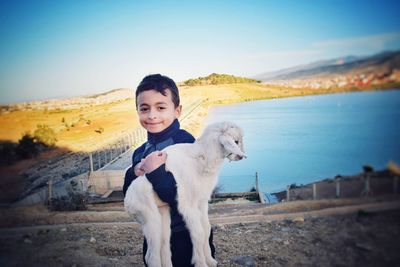 Portrait of cute boy holding goat outdoors