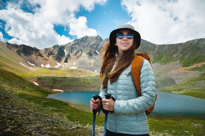 Female tourist enjoys the view of mountain peak rock and lake. idea of ecotourism. travel concept