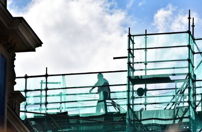 Low angle view of people working against sky