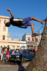 Young man performing stunt on tree trunk