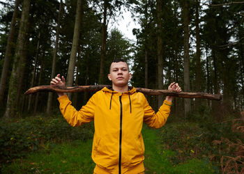 Portrait of young man holding stick at forest